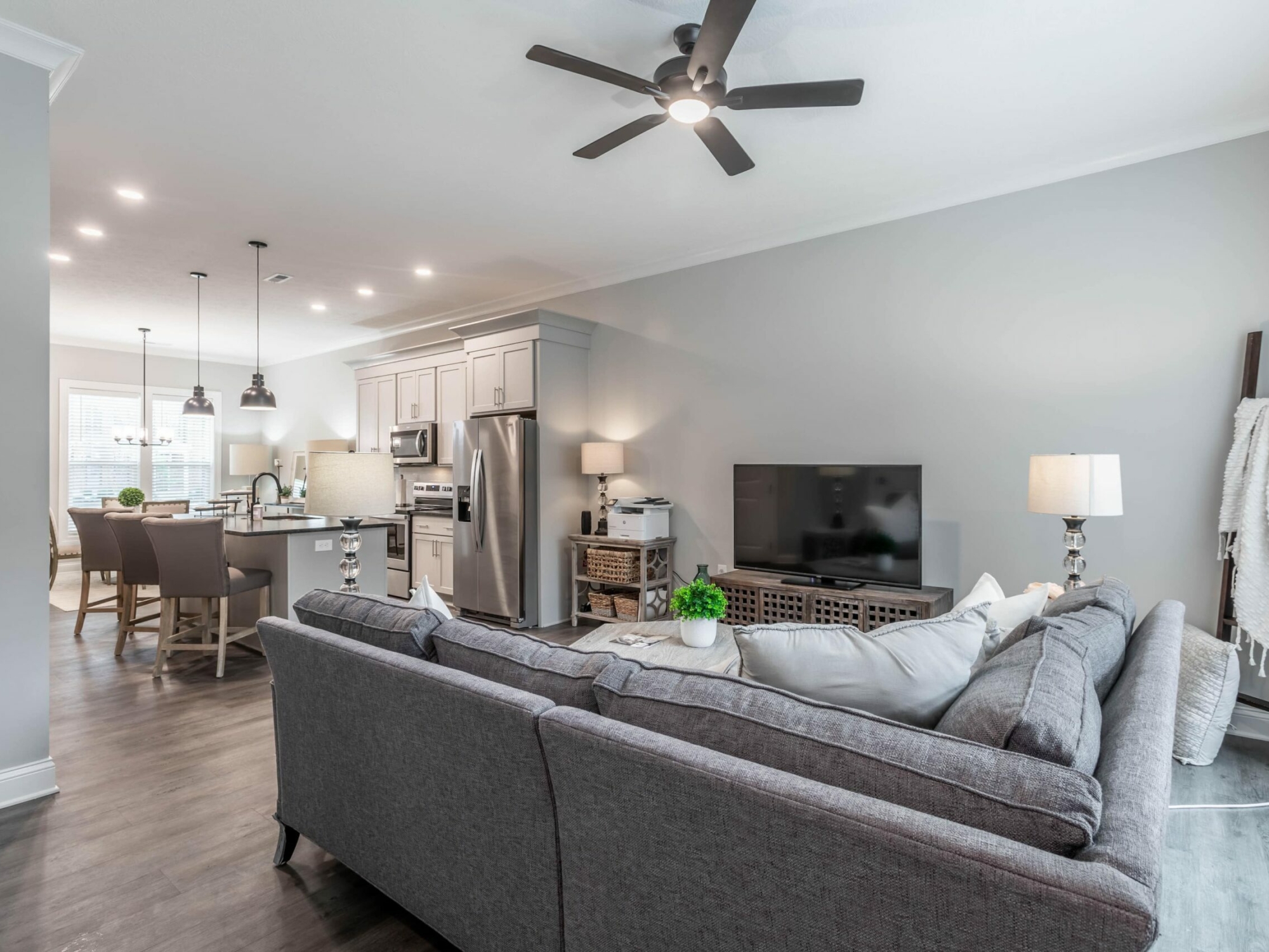 A living room with a gray couch and ceiling fan.