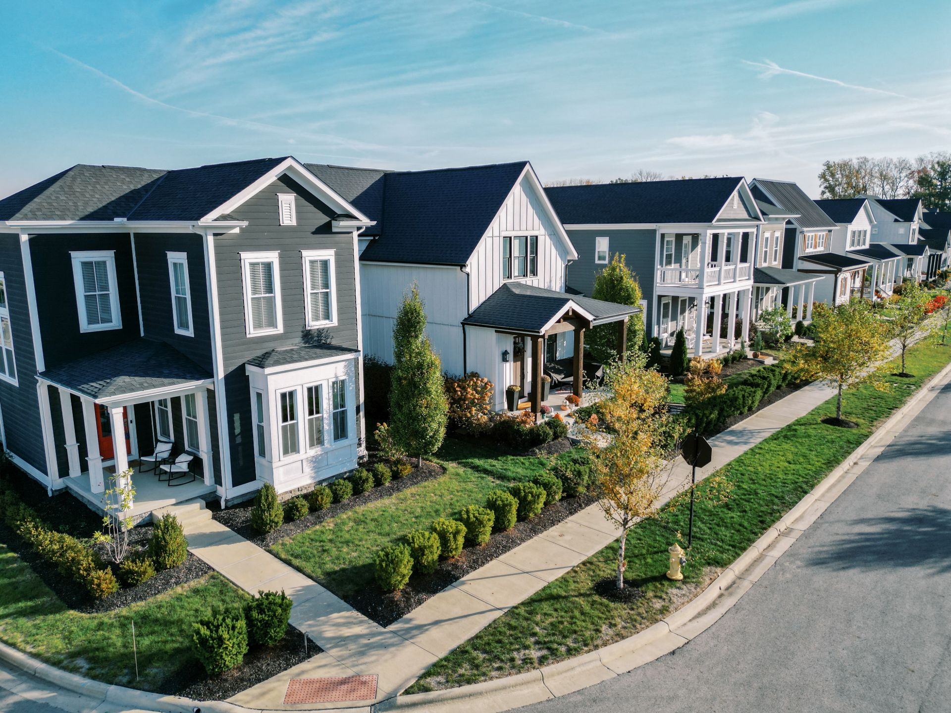A row of modern suburban houses with front porches, manicured lawns, and sidewalks on a sunny day—perfect for those looking to explore homeownership in Lewis Center.