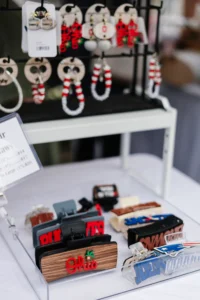 Display of earrings on a rack and custom Ohio-themed hair clips on a lower shelf at a vendor booth.
