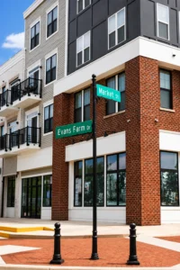 Street signs for Market St and Evans Farm Dr at a corner in front of a modern brick and white building with balconies and large windows.